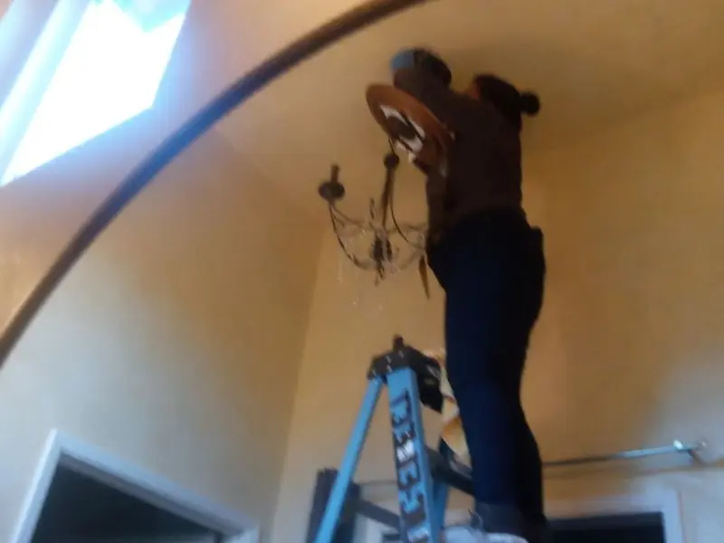 Electrician installing a chandelier in a Corrales residence